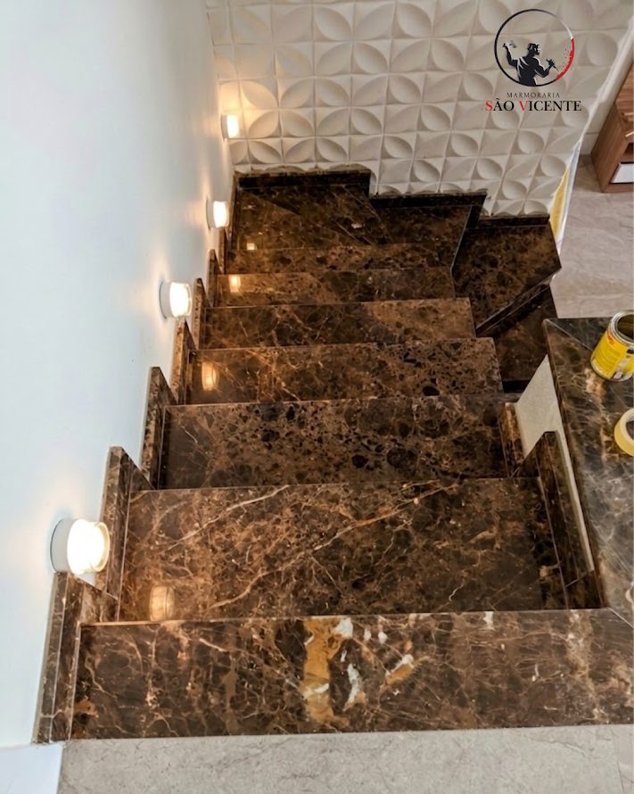 Escada revestida em mármore marrom com iluminação embutida na lateral