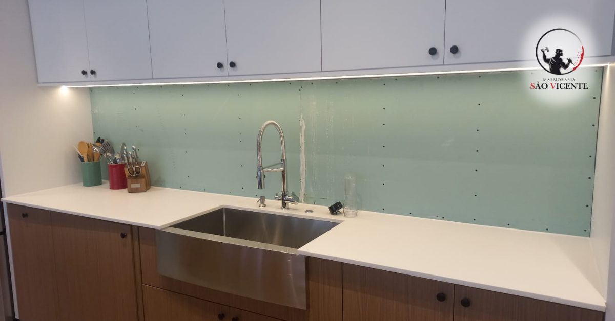 Bancada em pedra clara com cuba de inox instalada sob o tampo