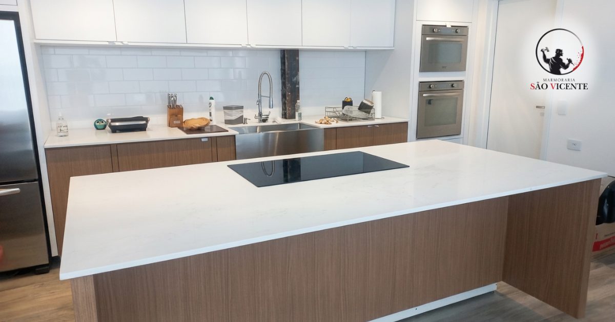 Ilha de cozinha com tampo em pedra clara e cooktop embutido