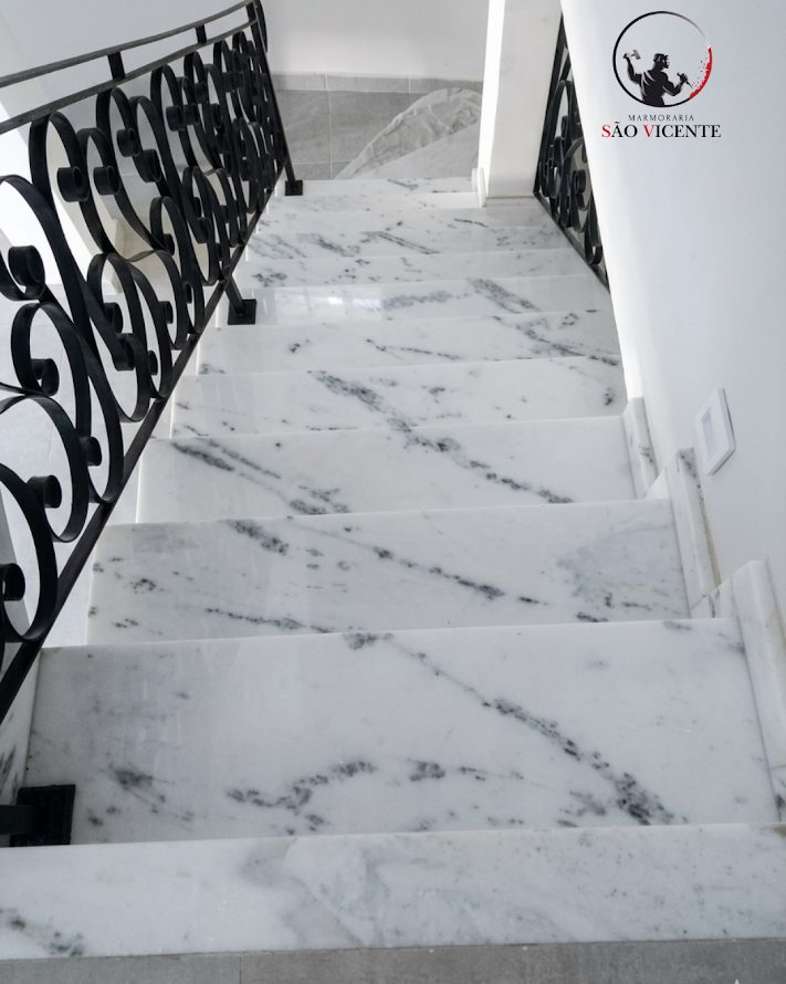 Escada revestida em mármore branco com corrimão de ferro